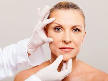 Cosmetologul examinează pielea feței pacientului